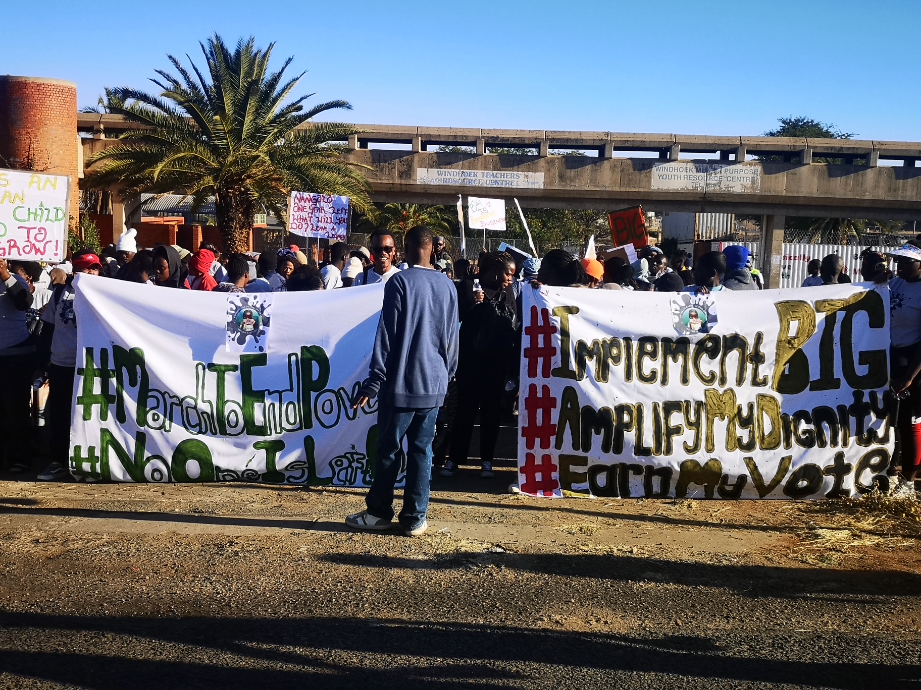 People holding Basic Income Grant campaign banners at a public action
